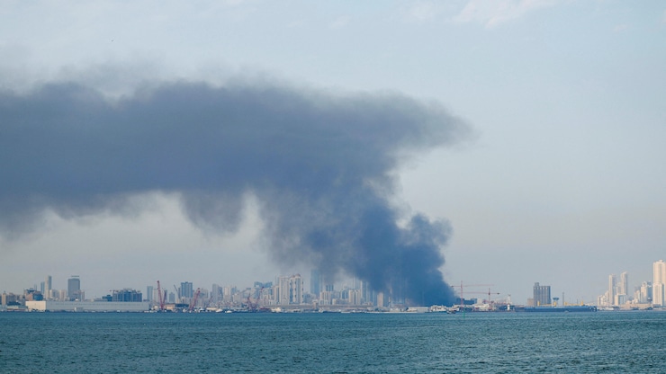 De la fumée s'élève au-dessus d'un port. 
