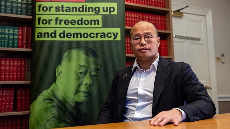 Un homme devant une affiche portant le portrait de son père.