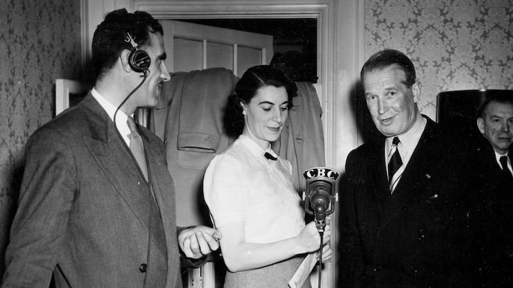 Une femme thin le micro à un homme. À ses côtés, un technicien du lad porte des écouteurs.
