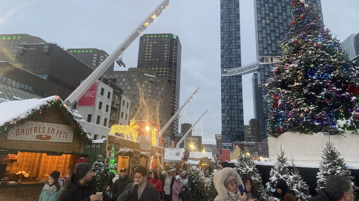 أشخاص أمام أكشاك وشجرة مضاءة.