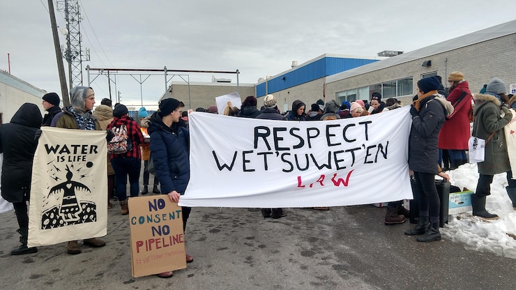 Manifestantes sostienen una pancarta en la que se lee "Respeten la ley de los Wet'suwet'en" y "Sin consentimiento, no al oleoducto".