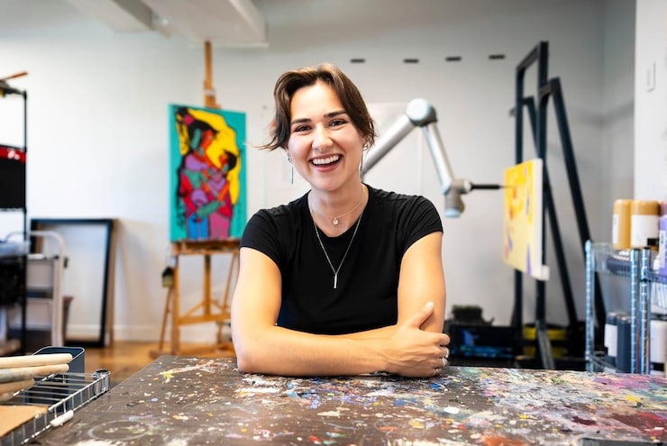 A woman smiling sitting in her workshop.