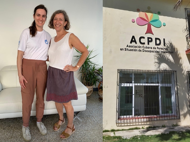 ES: Dos mujeres sonriendo de pie frente a un sofá blanco. Una lleva camiseta y pantalones, la otra blusa y falda. FR: Deux femmes souriant debout devant un canapé blanc. L'une porte un t-shirt et un pantalon, l'autre un débardeur et une jupe. EN: Two women smiling standing in front of a white couch. One wears a t-shirt and pants, the other a tank top and skirt.