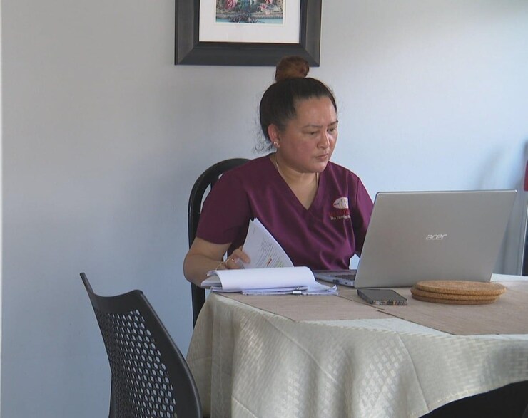 A woman looking at papers while using a laptop.