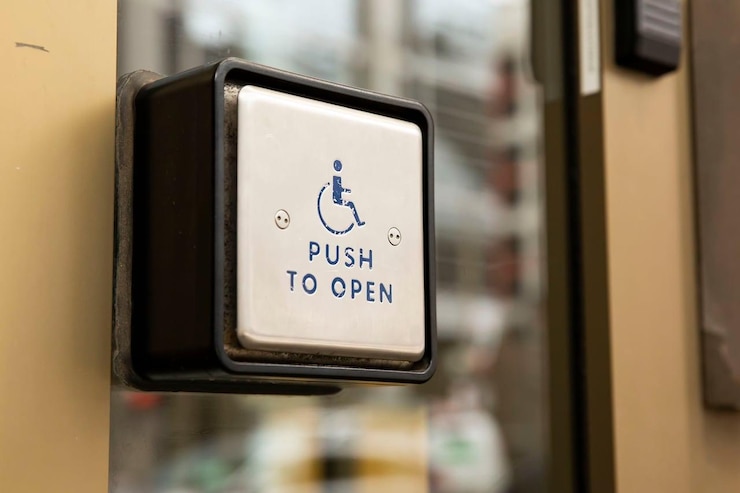 An automatic door button saying "Push to open" with a pictogram of a person in a wheelchair.