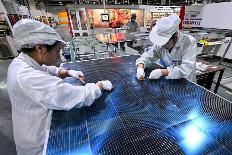 Two factory workers prepare a solar panel.