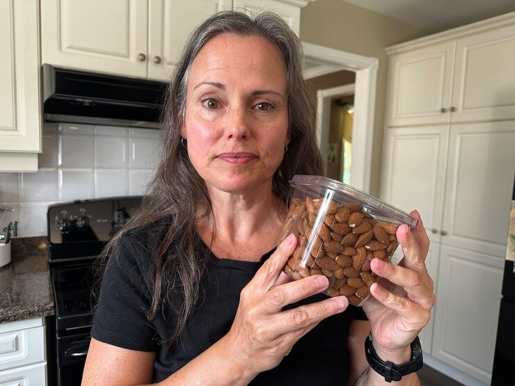 A woman holding a package of almonds.