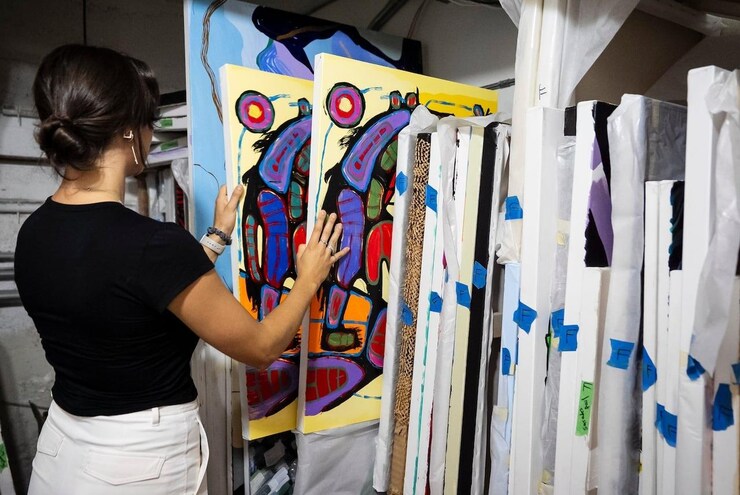 A woman looking at paintings filed in a storage area.