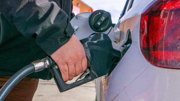 Une main tenant une pompe à essence en train de faire le plein.