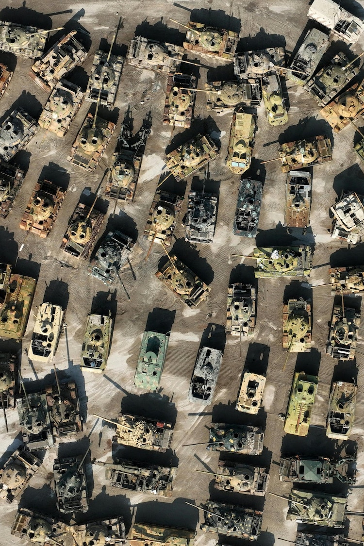 Des dizaines de véhicules blindés détruits sur un terrain désert.