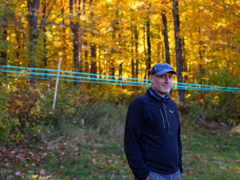 Sergio Rossi, professeur d’écologie forestière à l’Université du Québec à Chicoutimi (UQAC), devant une rangée d'érables aux feuilles dorées.