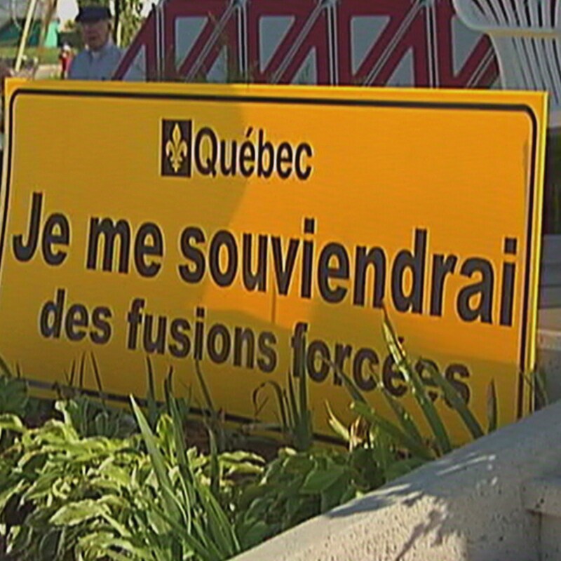 Une affiche portant l'inscription Je me souviendrai des fusions forcées.