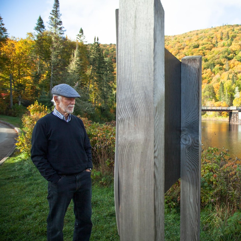 Jean Bédard se tient, debout, devant un panneau d'affichage, en bordure de la rivière.