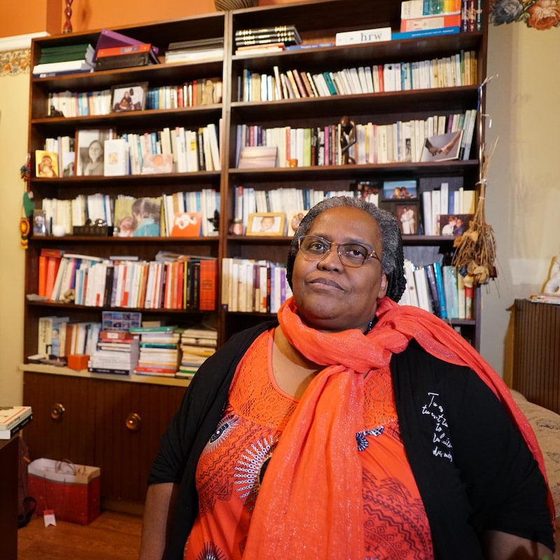 Jeanne-Marie Rugira est assise dans son bureau devant une grande bibliothèque pleine de livres.