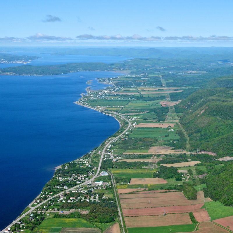 Paysage vu des airs de la côte de Carleton, sur mer, en Gaspésie avec des lots de terre et un cours d'eau.