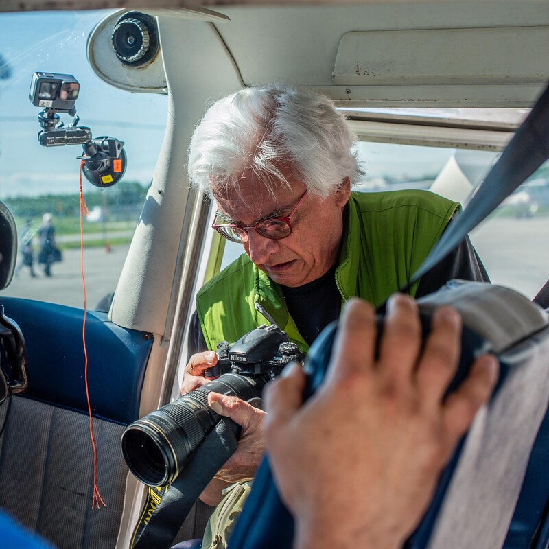 Un homme regarde son appareil photo à bord d'un petit avion.