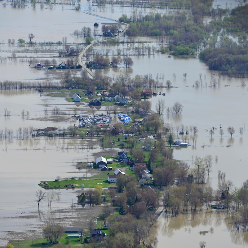 Des maisons et une route entourés d'eau lors d'inondations.
