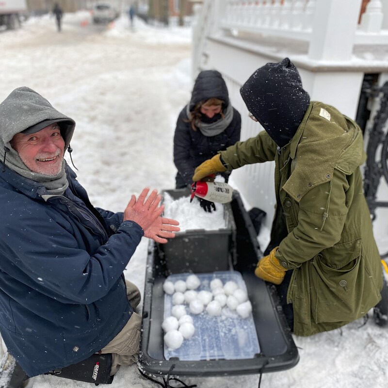 Des membres de l’équipe préparent des boules de neige qui sont empilées dans un traîneau.
