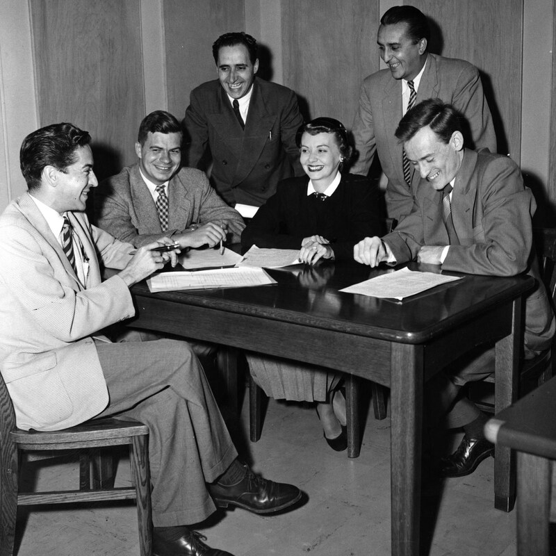 Assis autour d'une table dans un studio de radio, Fernand Seguin, Jacques Dupire, Raymond Laplante, Nicole Germain, Jean-Paul Nolet et Jean-Louis Roux.
