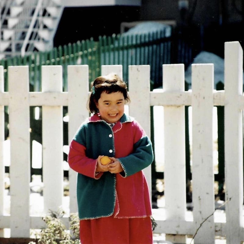 Daphné-Anne Olepika, alors qu'elle était une petite fille, debout devant une clôture.