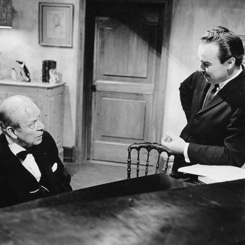 Henri Bergeron conversant avec Wilfrid Pelletier, assis à un piano.