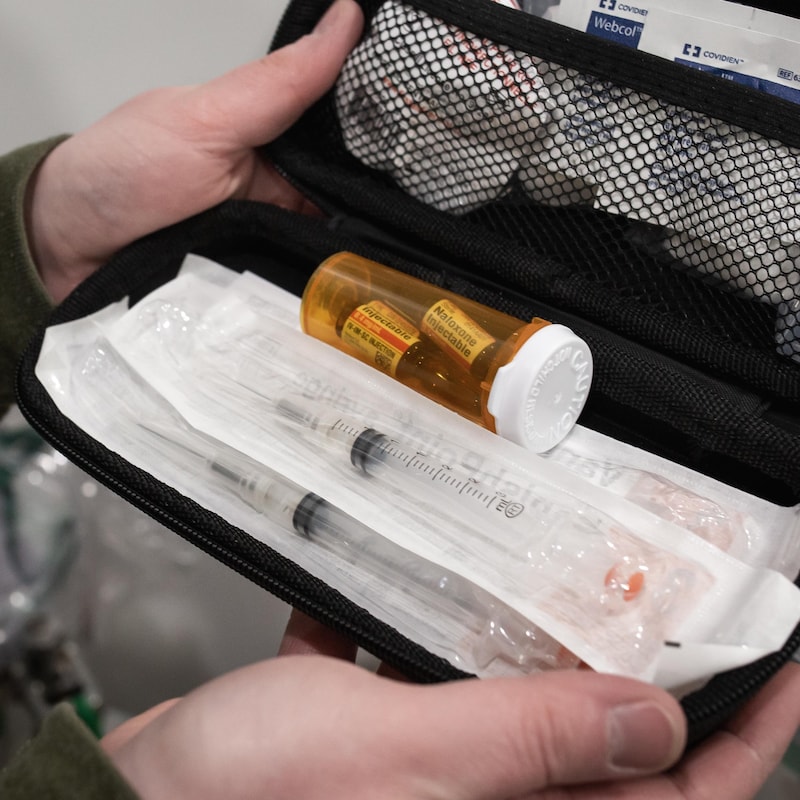 Jason Mercredi tient dans ses mains une trousse médicale contenant des seringues, des drogues et de l'équipement pour venir en aide aux toxicomanes.
