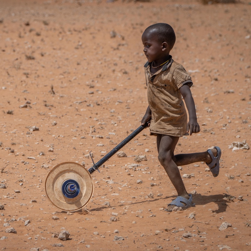 Un enfant pousse une roue.