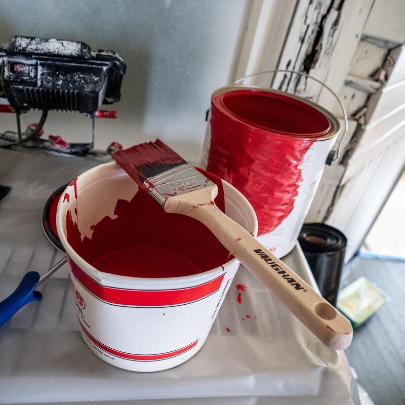 Un pot de peinture et un contenant avec de la peinture, un pinceau est posé dessus, en Alaska, juillet 2022.