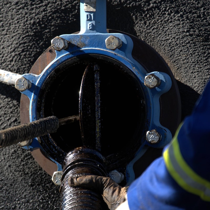 L'entrée d'un puits de pétrole avec un tuyau inséré à l'intérieur par une personne en bleu de travail, près de Frog Lake, en Alberta, en octobre 2022.