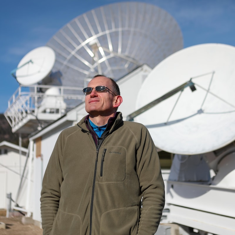 Andrew Gray devant deux imposants radiotélescopes, à l’Observatoire fédéral de radioastrophysique près de Penticton, en février 2024.