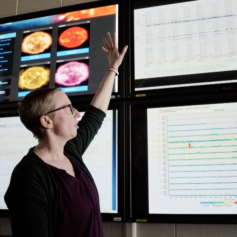 Robyn Fiori en train de montrer des images de graphique, sur des écrans au mur, au Centre canadien de météo spatiale, près de Saskatoon, en février 2024.
