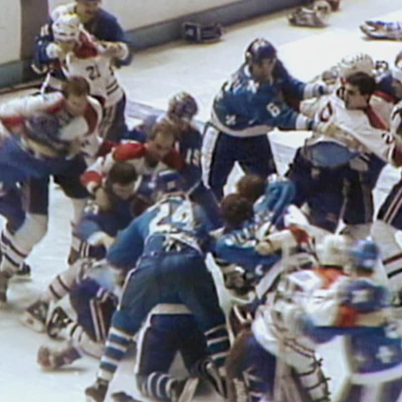 Les joueurs des deux équipes s'échangent des coups sur la glace.