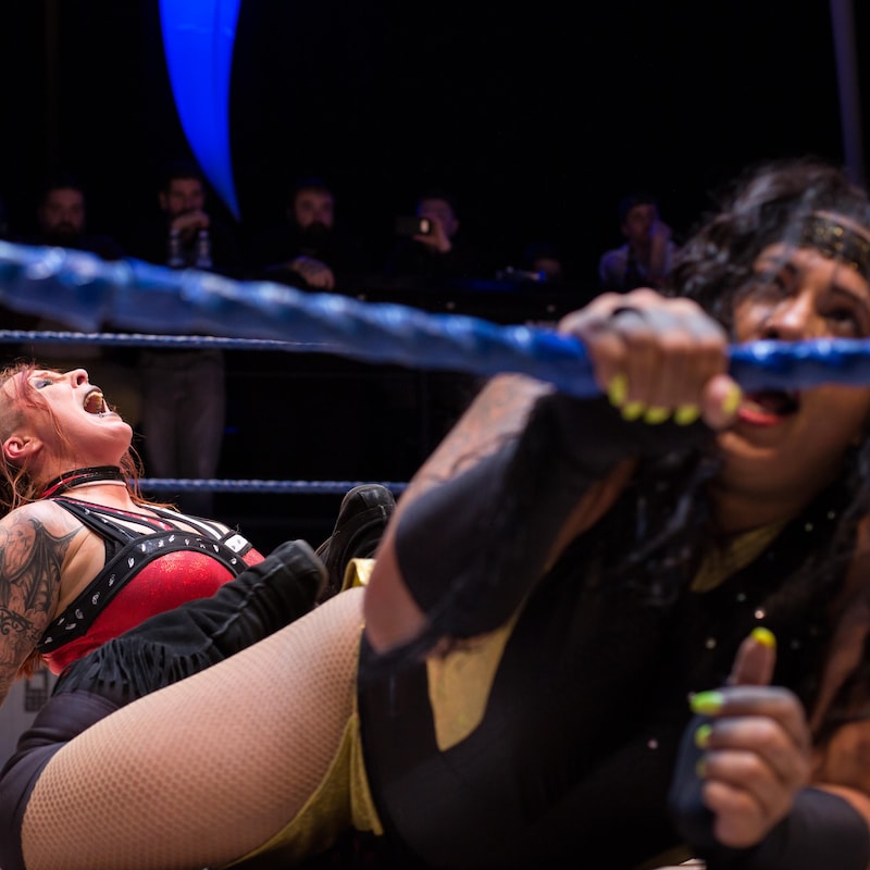 Nyla Rose agrippe la première corde du ring tandis que LuFisto coince ses jambes dans les siennes.