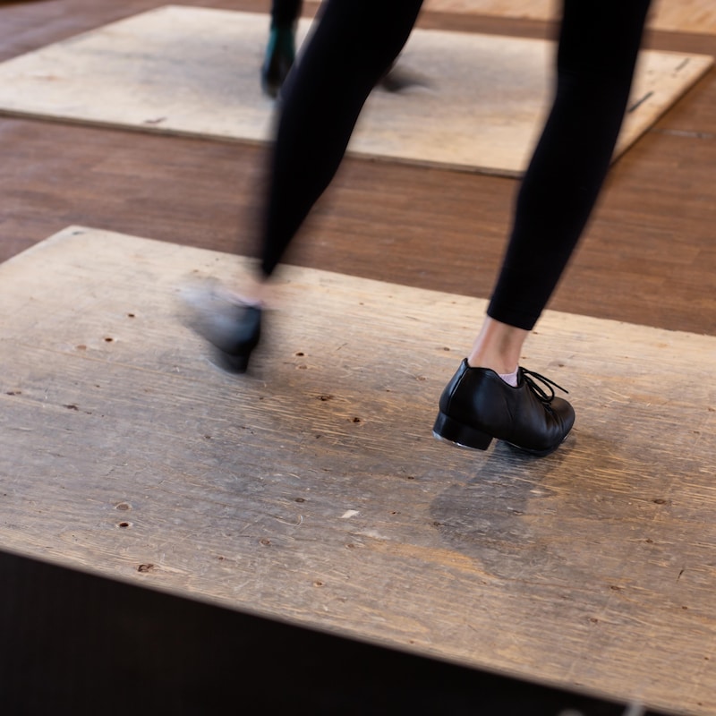 Des chaussures à claquettes frappent des planches en bois.