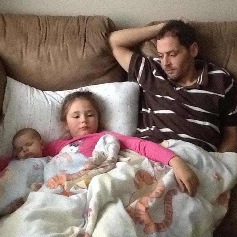 Deux fillettes et leur père couchés sur un divan.