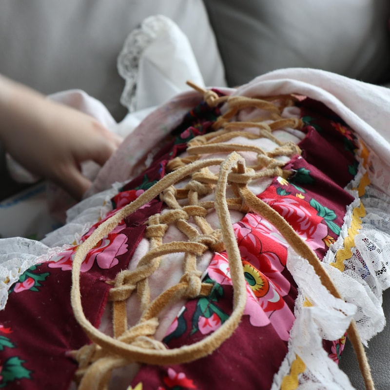 Un Waspsuuyan, une couverture traditionnelle faite avec un tissu à fleurs et de la dentelle, maintenue par une cordelette en cuir.