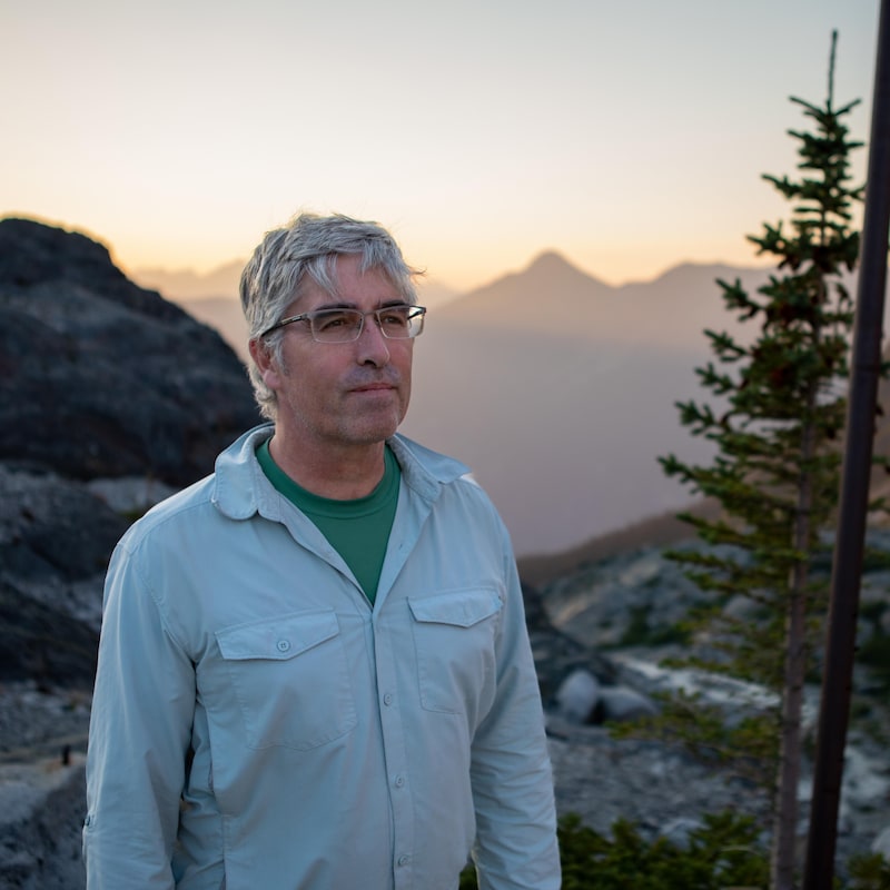 Portrait de Brian Menounos dans un paysage de montagne.