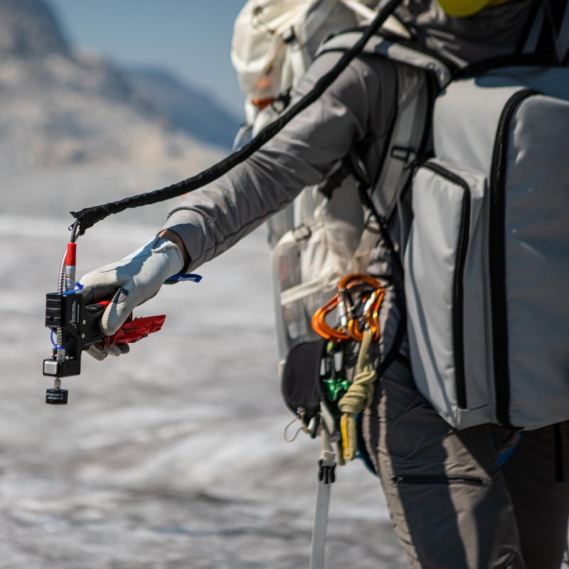 Adam Hawkins tient un appareil de mesure au-dessus d'un glacier.