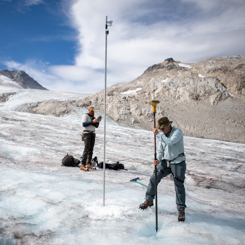 Deux hommes enfoncent des piquets dans la glace.