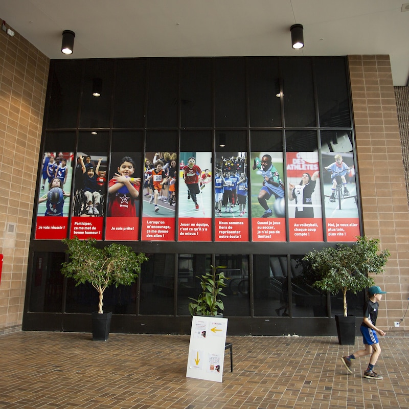 Des affiches de jeunes pratiquant des sports, dans l'entrée du complexe sportif.
