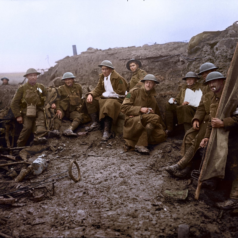Des soldats, dont plusieurs portent des bandages, sont accroupis dans la boue.