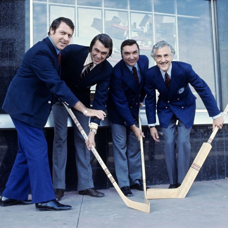 À l'extérieur, debout devant l'édifice du Forum de Montréal, Gilles Tremblay, Richard Garneau, Lionel Duval et René Lecavalier avec des bâtons de hockey dans les mains.