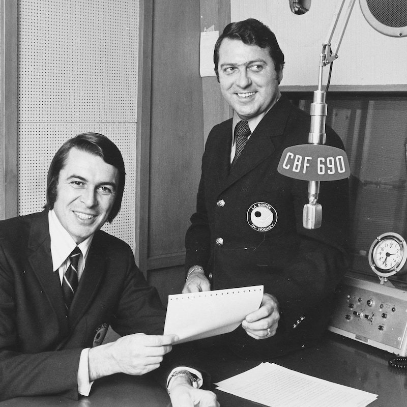 Richard Garneau et Gilles Tremblay dans un studio radio, souriant en tenant une feuille de route.