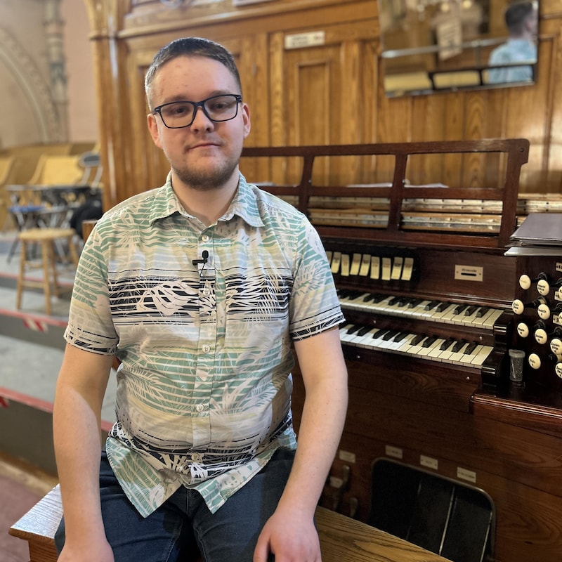 Thomas Fortin, assit près d'un orgue Casavant.