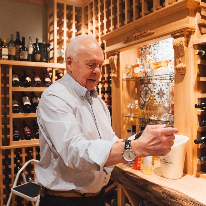 Un homme tient une bouteille dans sa cave à vin.