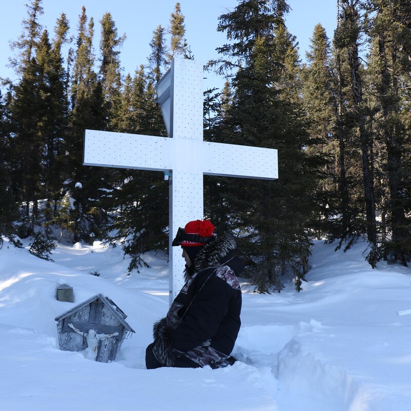 Marcellin Michel est à genoux dans la neige devant des croix.
