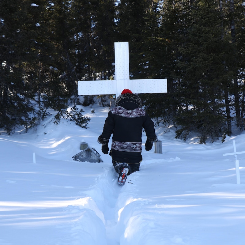 Marcellin Michel trace un chemin dans la neige devant une croix.