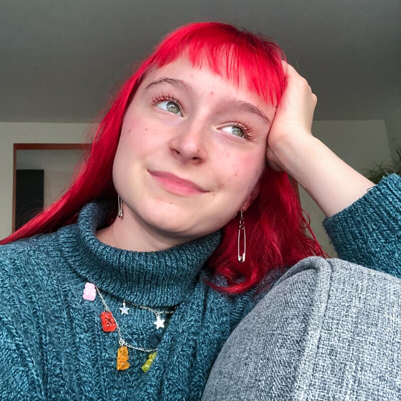 L'adolescente aux cheveux rouges regarde au ciel en souriant.