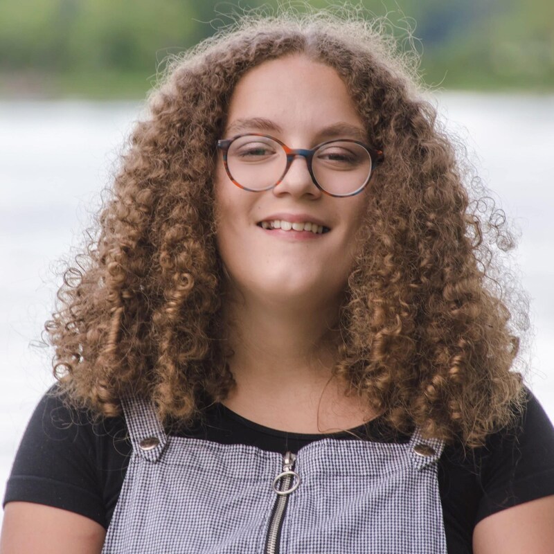 L'adolescente sourit près d'un lac.