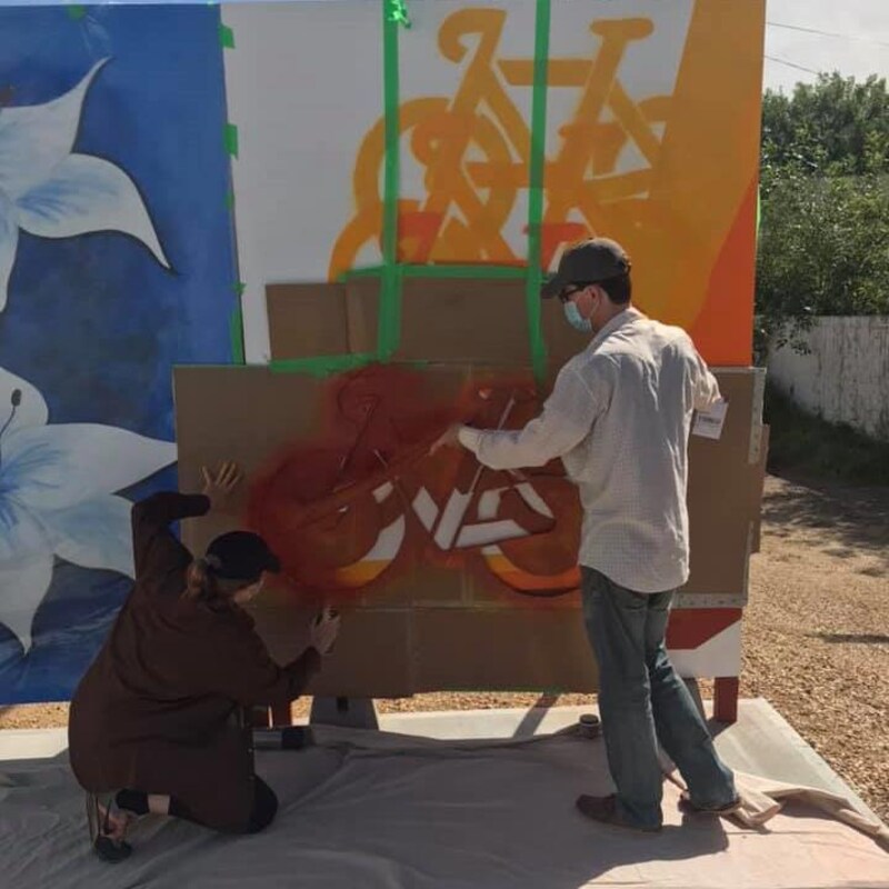 Deux artistes en train de peindre un tableau dans une oeuvre murale.